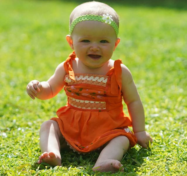 a baby smiling in the grass