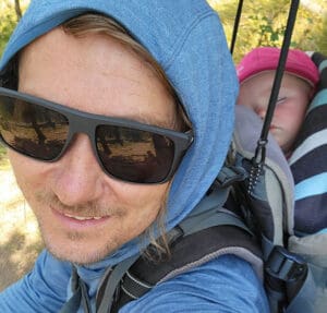 steve andrews hiking with his baby in a backpack, fast asleep