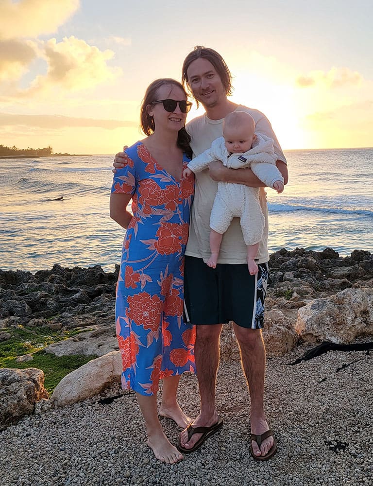 a family standing next to the ocean at sunset in Hawaii