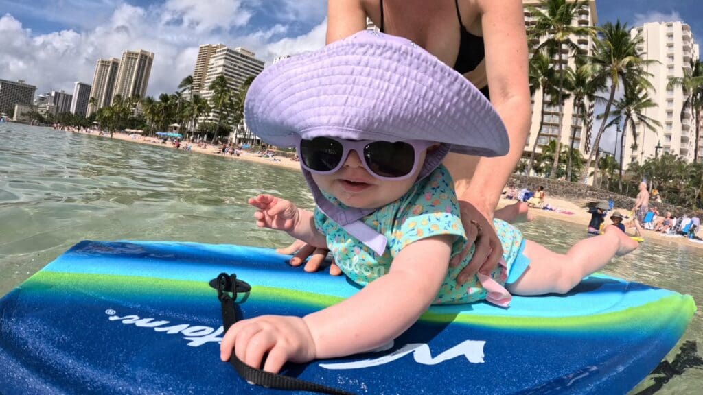 a baby sits on a boogie board at waikiki beach in hawaii