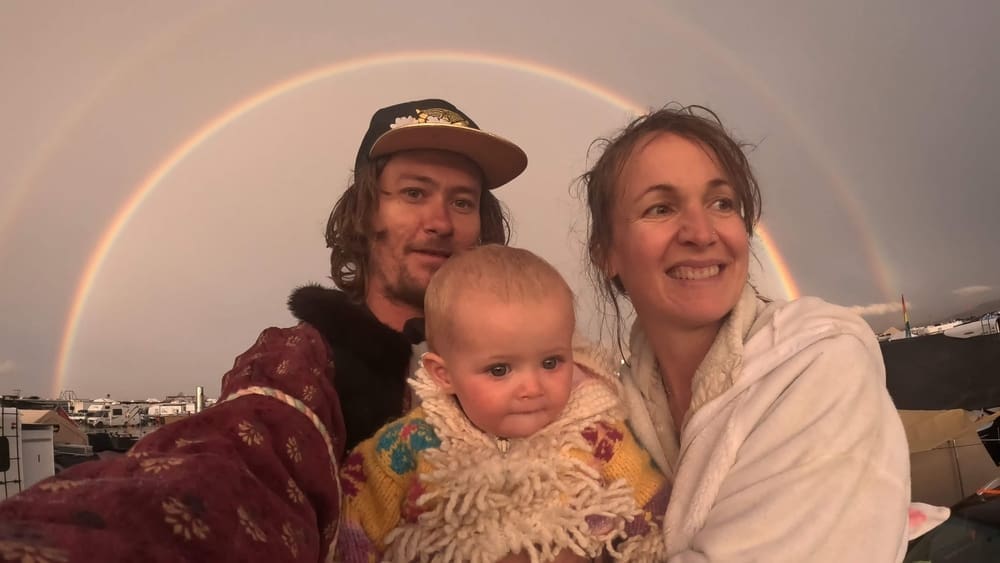 a family posing in front of a magnificent rainbow at burning man