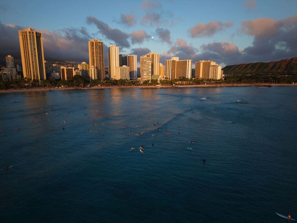 a view of waikiki beach at sunset with the moon rising in the background