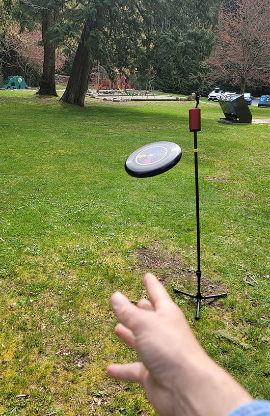 a flying disc moves through the air toward a target in the park