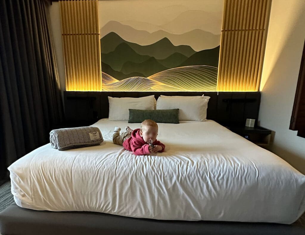 a baby lies on a queen sized bed at the Nita Lake Lodge in Whistler British Columbia