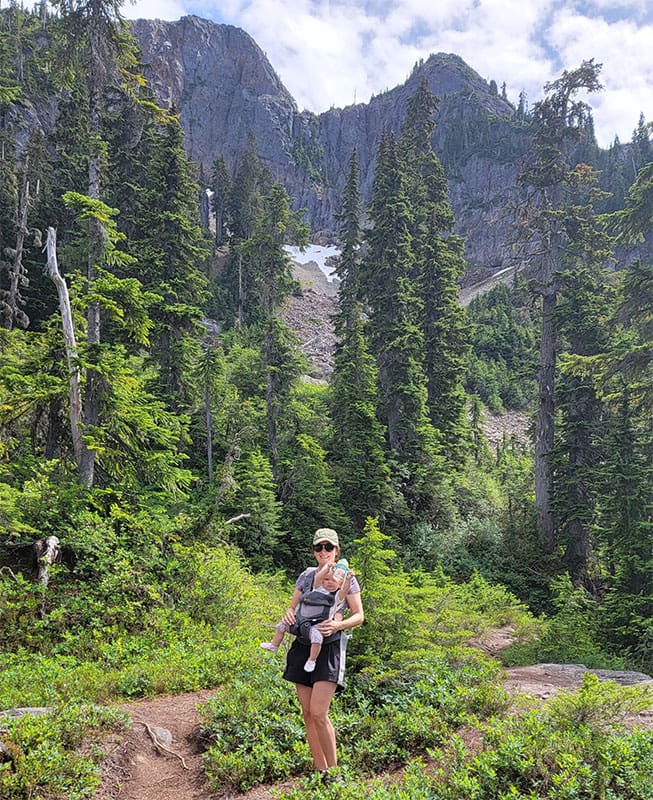 a mother hikes in the subalpine of sky pilot mountain with her baby daughter on her chest