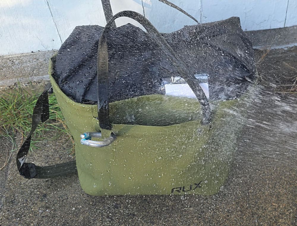 testing the waterproofing on the RUX waterproof beach tote by spraying it with a hose.