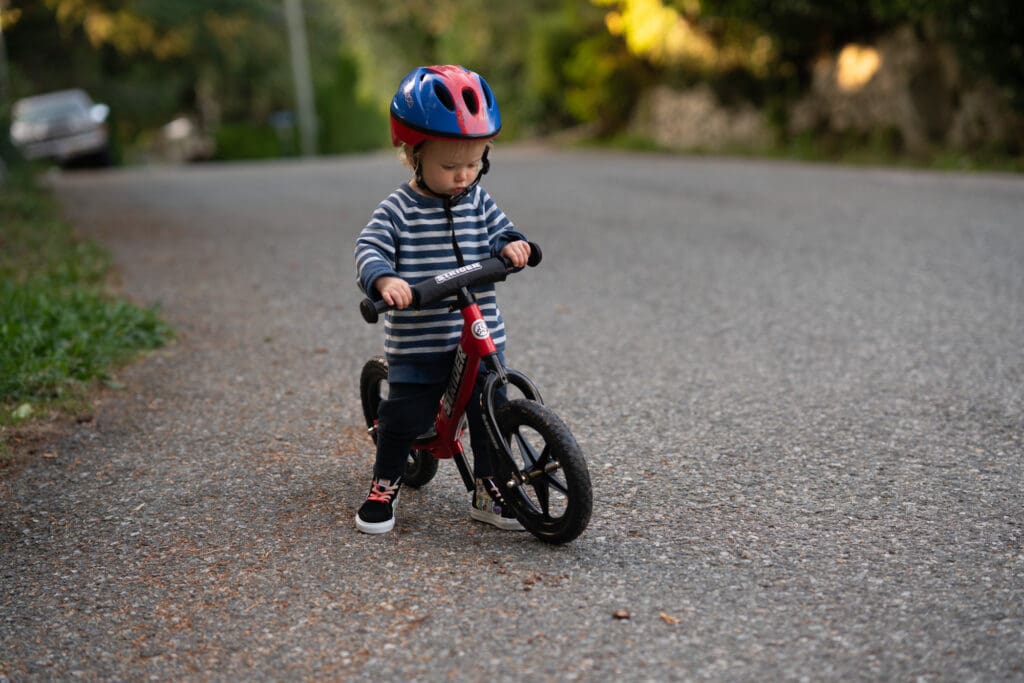 a young child learns how to use his strider balance bike