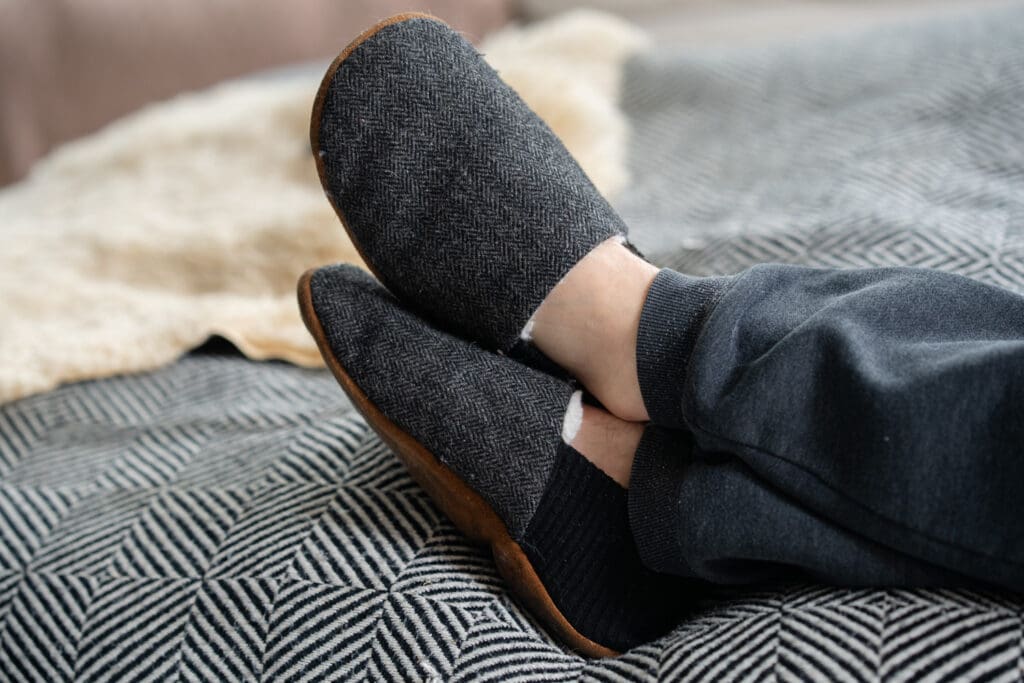 a close up image of a person wearing the kolo house shoes on a couch