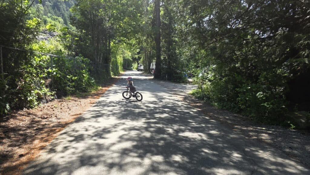 a child rides her bike in the campground at porteau cove provincial park