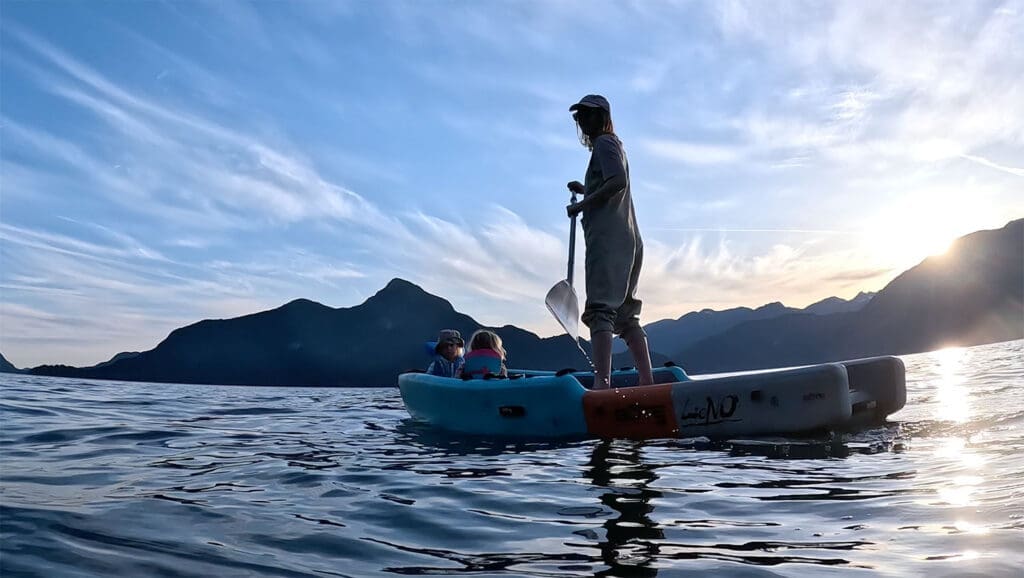 a woman paddles at sunset on a SUP with her children in howe sound british columbia