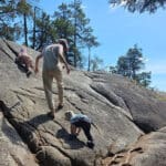 a mom and two toddlers hike up a granite rock in murrin provincial park near squamish bc