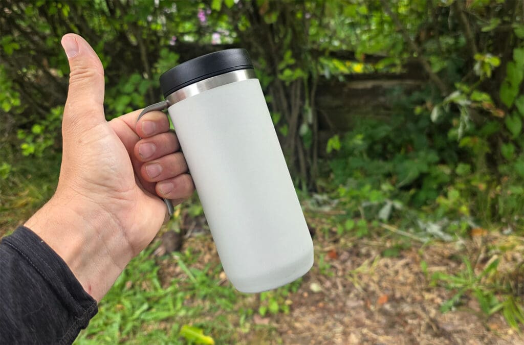 holding a purist coffee mug in the hand with a thumbs up