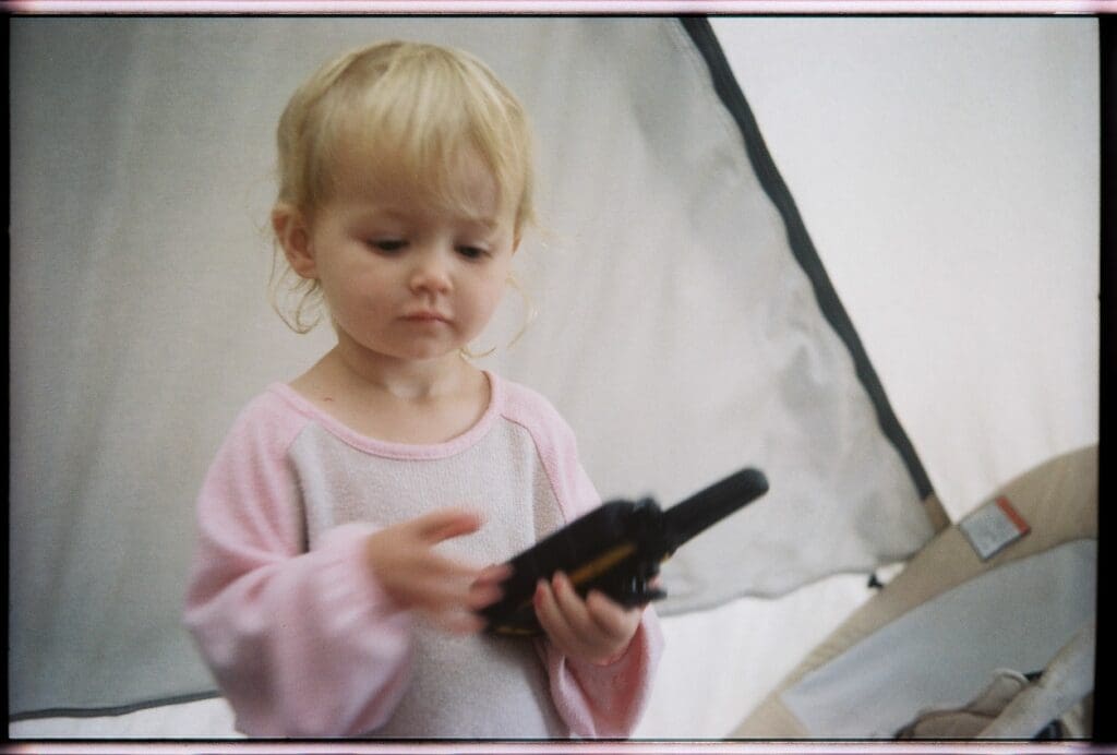 Toddler playing with a walkie talkie, while taking shelter inside our tent during a rainstorm while camping