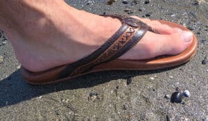 a mans foot inside teh leather flip flops by olukai and new heights
