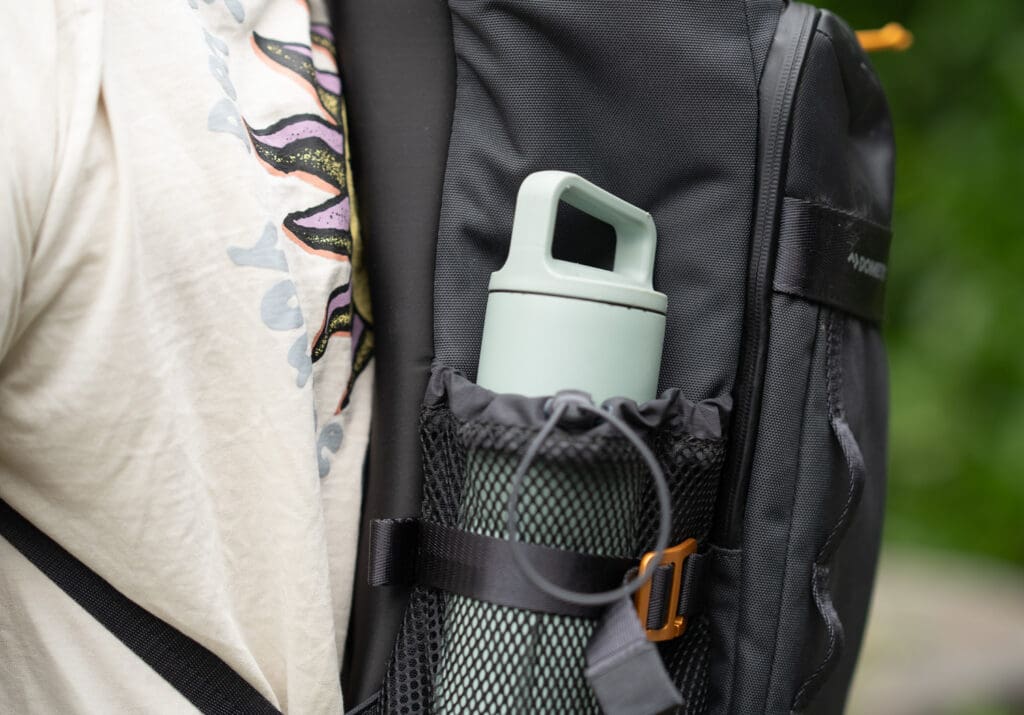 a close up view of the dometic unrestricted backpack cooler with the water bottle pocket on the side