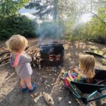 two kids sit in front of the campfire